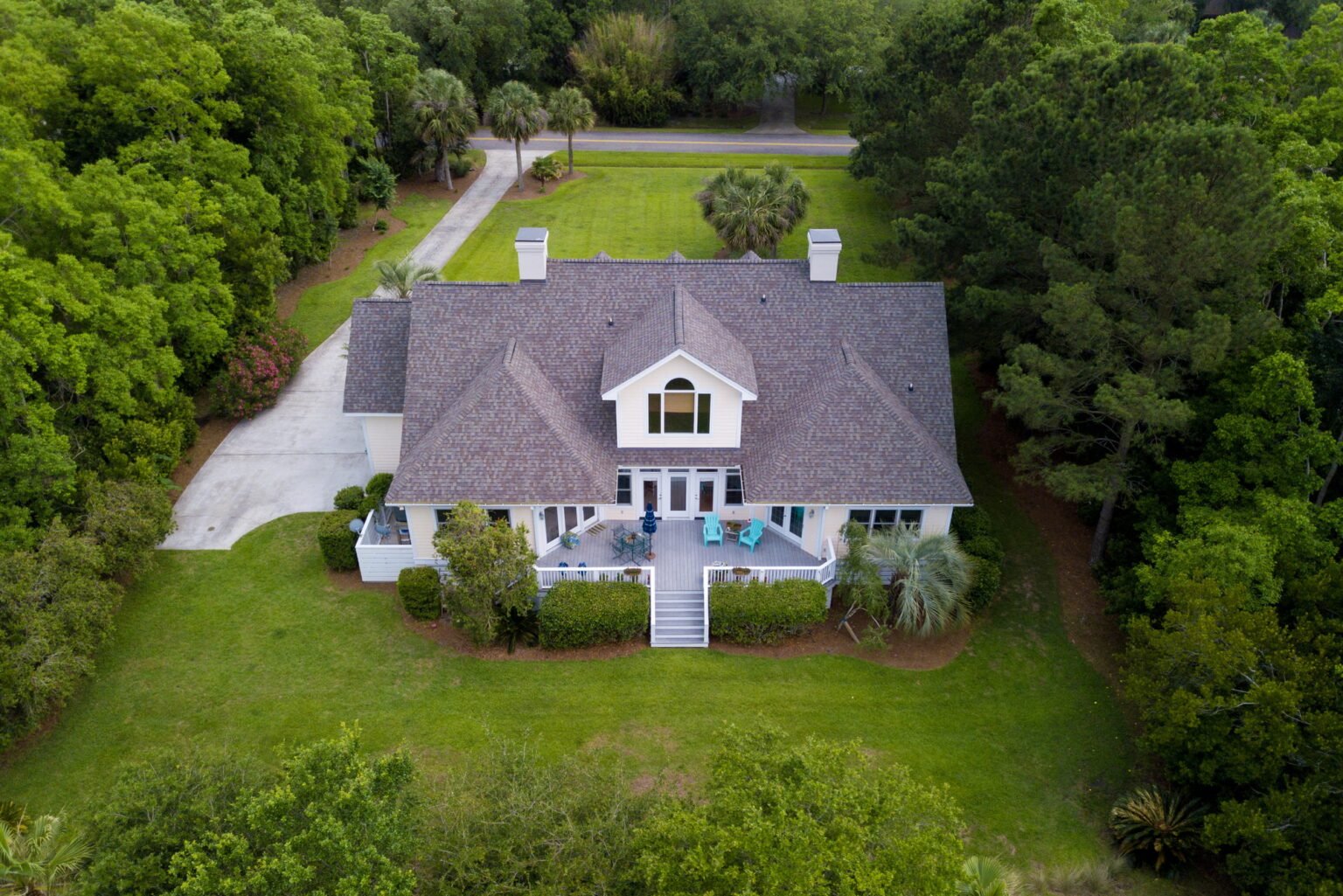 Aerial view of large home with new roof on wooded grassy propert